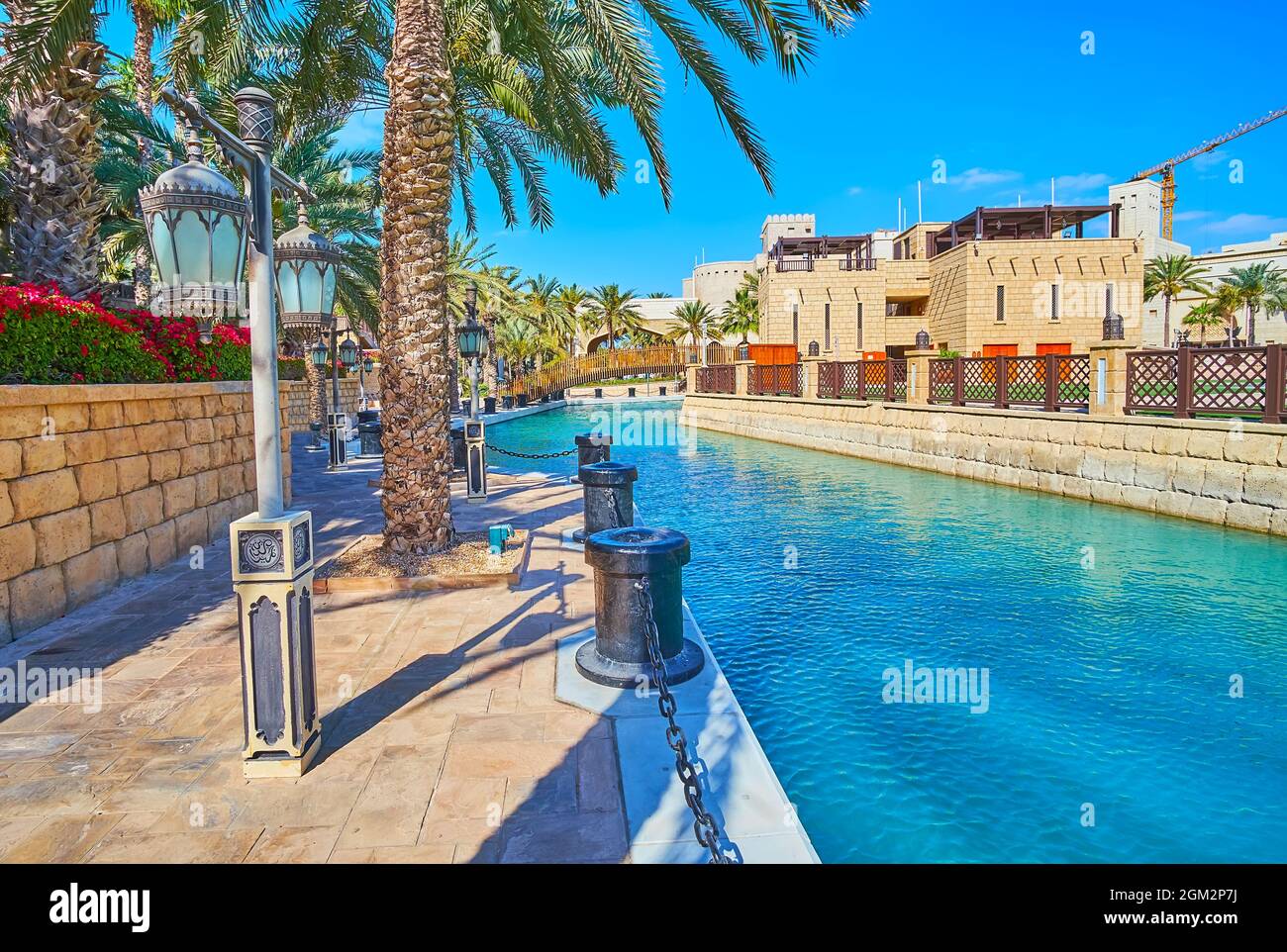 Der angenehme Spaziergang am Kanal des Souk Madinat Jumeirah Marktes mit Blick auf Fort Island und den malerischen grünen Garten, Dubai, VAE Stockfoto