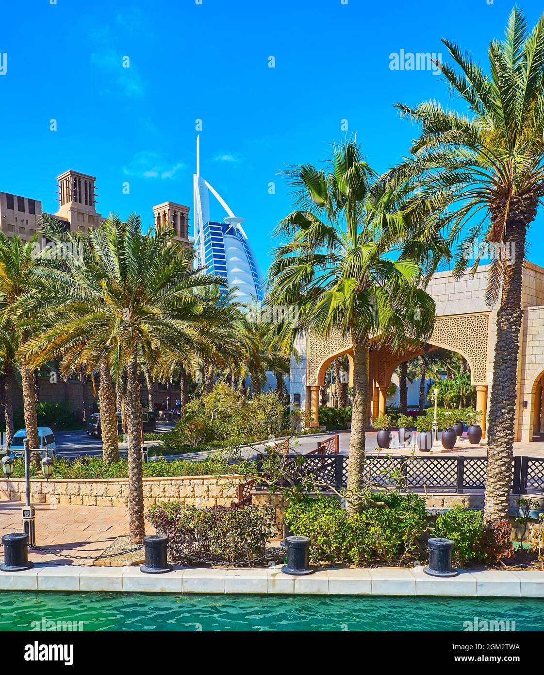 Die üppigen Palmen am Kanalufer des Souk Madinat Jumeirah-Marktes mit Blick auf Burj al Arab im Hintergrund, Dubai, VAE Stockfoto