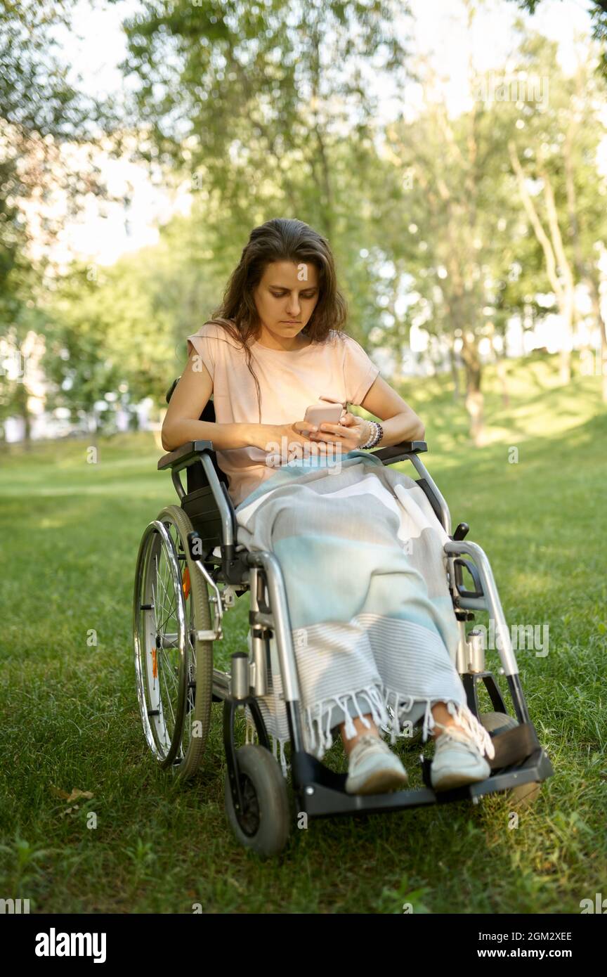 Behinderte Frau im Rollstuhl mit Mobiltelefon Stockfoto