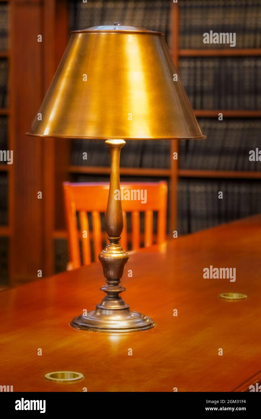 New York Public Library Quiet Room – Blick auf einen leeren Holztisch, eine beleuchtete Messinglampe und Bücherregale im Hintergrund. Die NYPL Stephen A. S Stockfoto