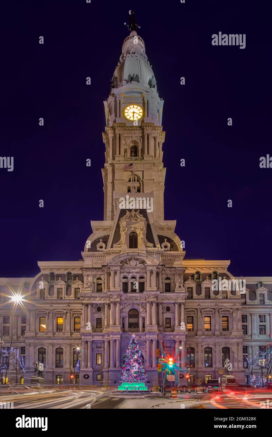 Philadelphia City Hall - Blick auf das beleuchtete Rathaus in der Dämmerung. Die lange Belichtung erzeugte leichte Spuren der vorbeifahrenden Fahrzeuge und des CO Stockfoto