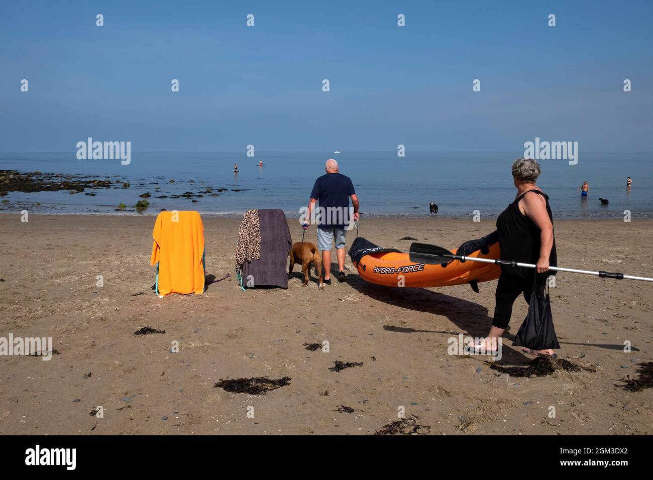 Älteres aktives Seniorenpaar am Sandstrand von New Quay in Ceredigion an der walisischen Küste mit Kajak und Liegestühlen Wales UK KATHY DEWITT Stockfoto