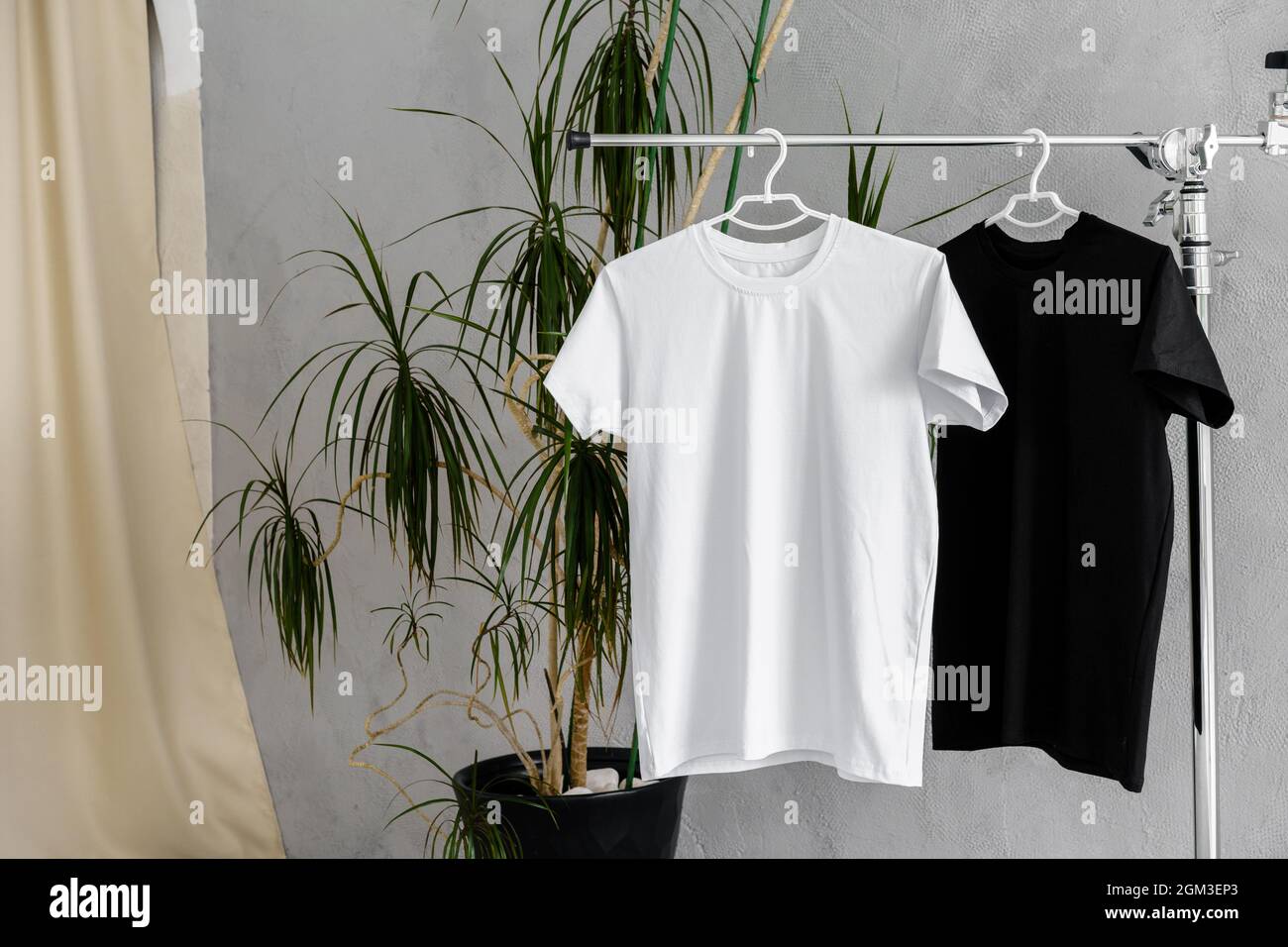 Weiße und schwarze T-Shirts auf Kleiderbügeln für die Designpräsentation Stockfoto