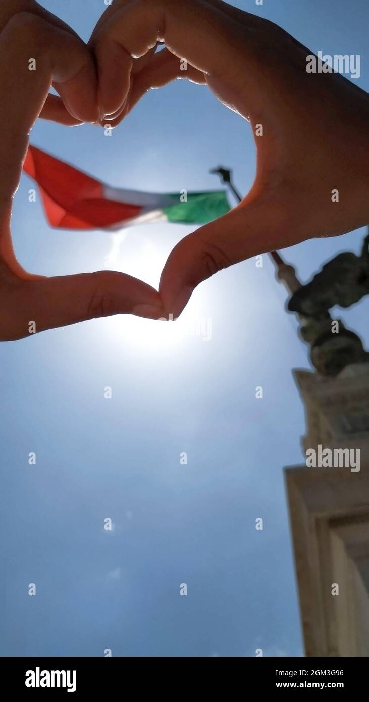 Geste mit Händen, die Symbol für Herz und Liebe über die italienische Nationalflagge zeigt. Frau, die ihre Liebe zur italienischen Flagge zeigt Stockfoto