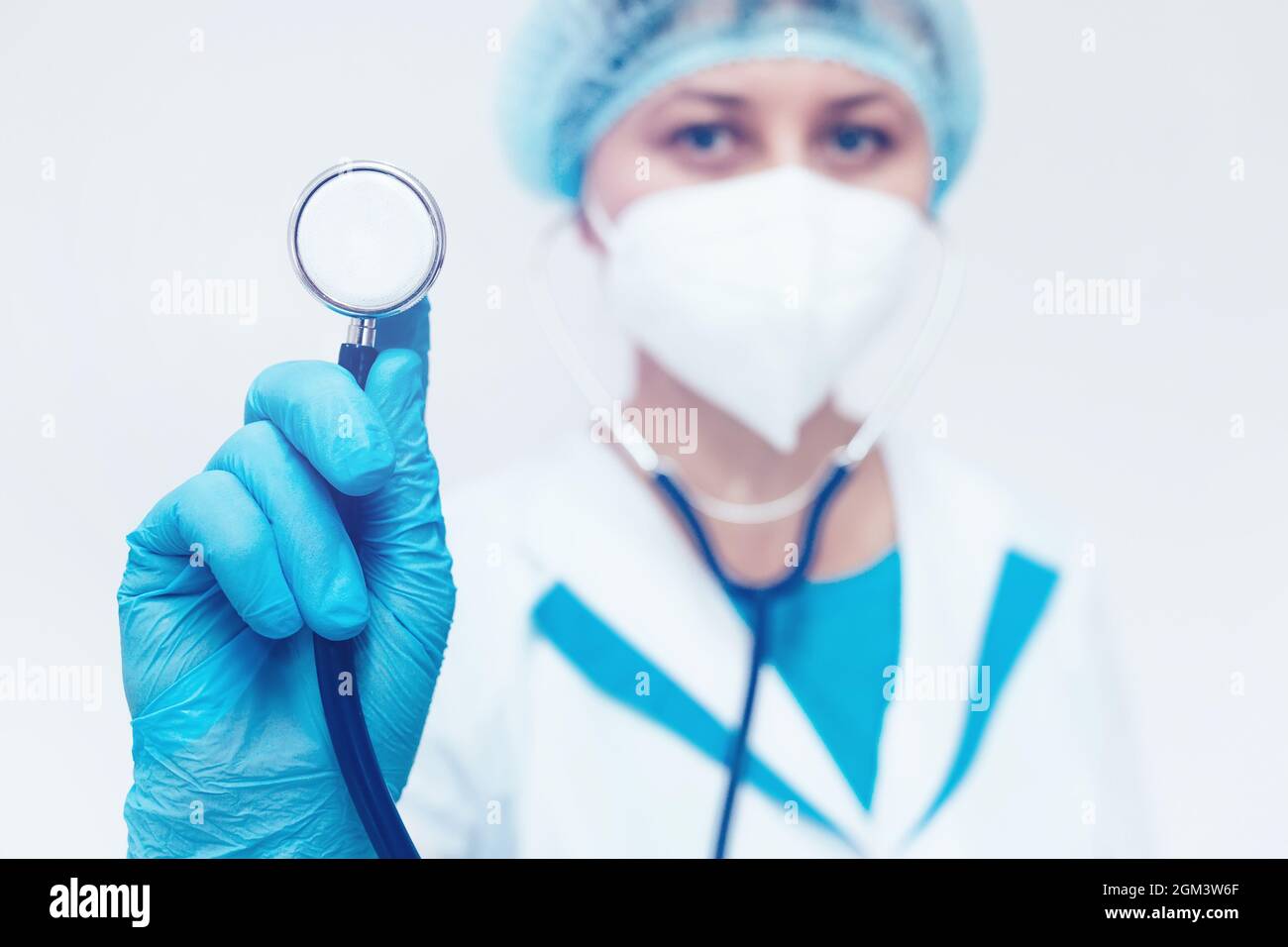 Ein Kardiologe in einer medizinischen Maske hält ein Stethoskop in der Hand. Herzuntersuchung und ärztliche Untersuchung. Stockfoto