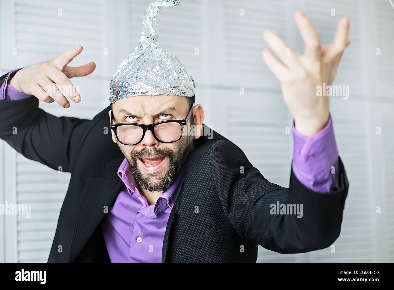 Bärtiger lustiger Mann mit Kappe aus Aluminiumfolie. Konzept Kunst Phobien. Verschwörungstheorie. Verschwörung. Wahnsinn. Stockfoto