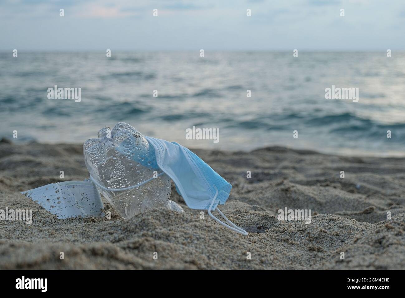 Schützende Gesichtsmaske und Plastikflasche auf marine Ökosystem, covid Verschmutzung Abfälle verworfen Stockfoto