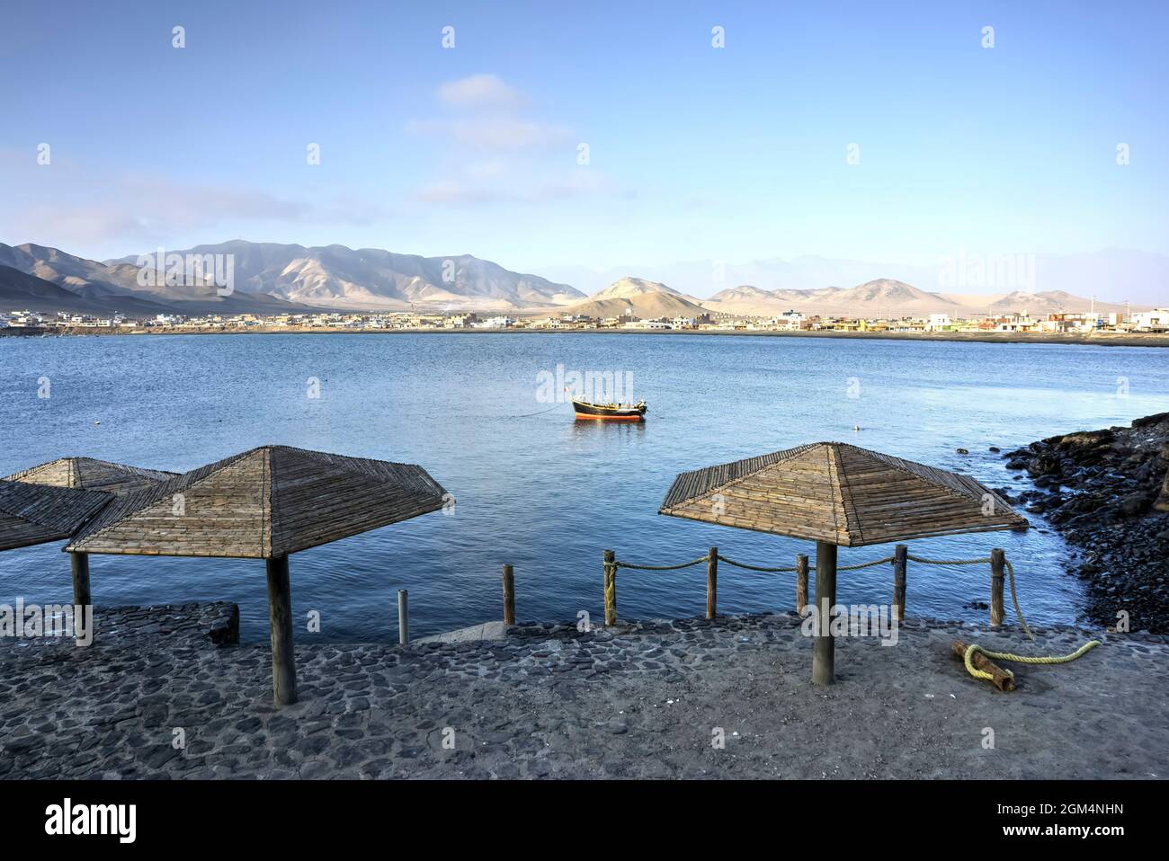 Tortugas, Casma, Peru - 03. August 2021: Blick von Tortugas über die Bucht mit Bergen im Hintergrund und Regenschirmen im Vordergrund Stockfoto