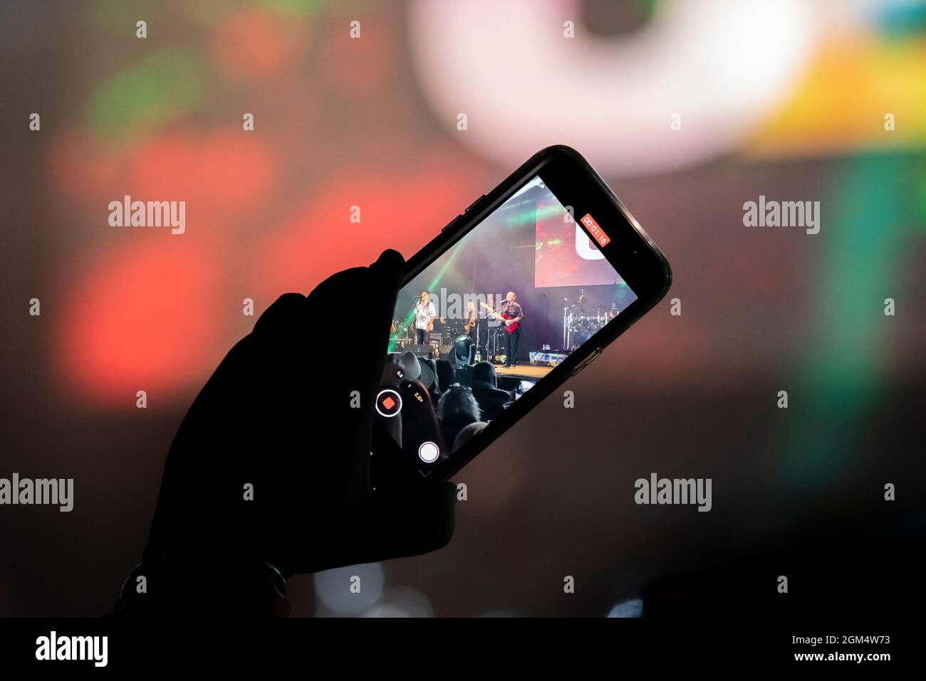 Person, die ein Konzert mit einem Mobiltelefon aus dem Publikum filmt. Nachtmusikfestival über den Bildschirm eines Mobiltelefons. Live-Show-Aufzeichnung Stockfoto