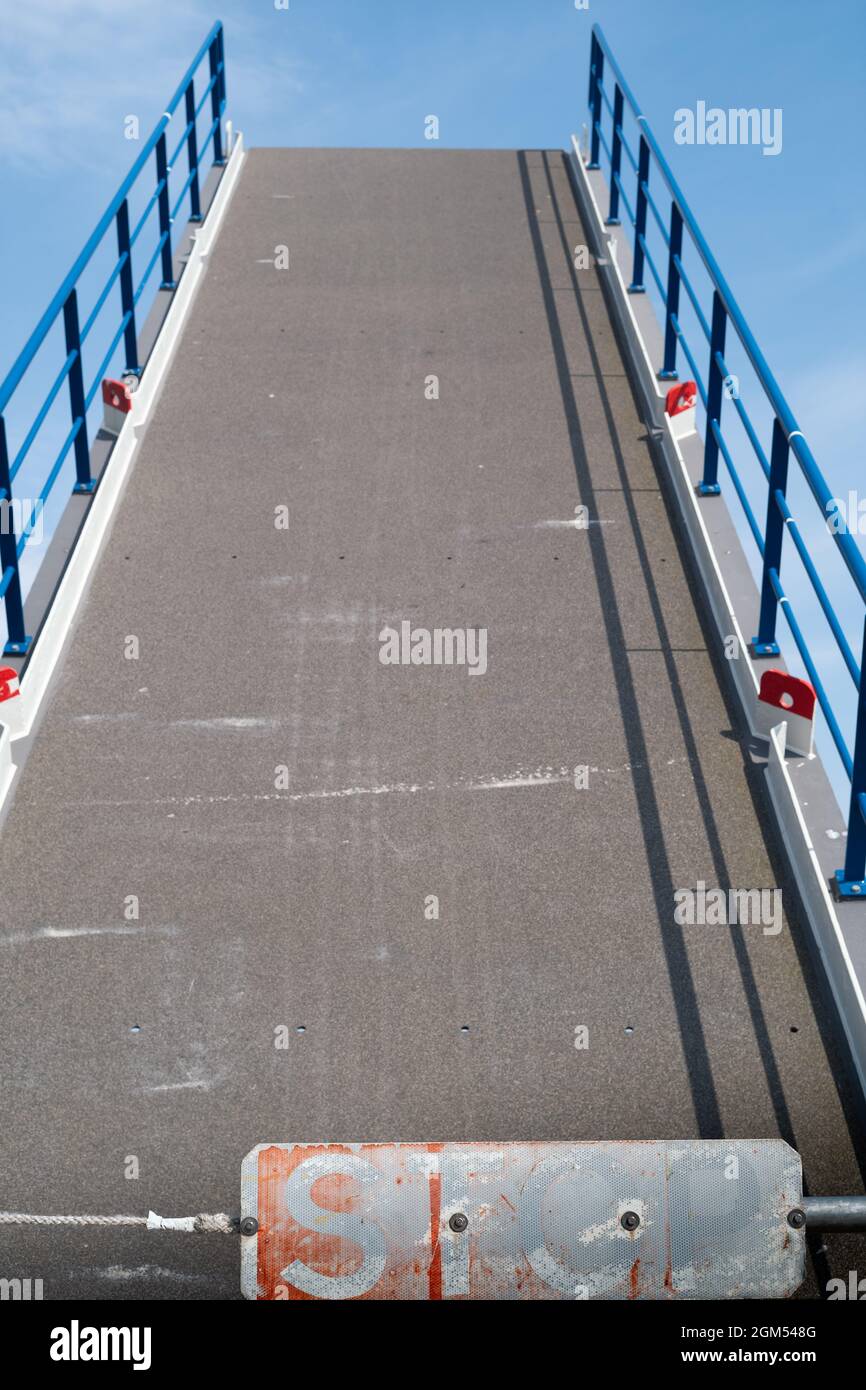 Ein verblassenes, abgenutztes Stoppschild am Boden einer Zugbrücke, das sich öffnet und nach oben hebt. Stockfoto