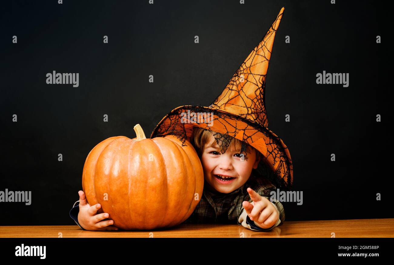 Frohe Halloween. Kleiner Junge im Hexenhut mit halloween Kürbis, der auf dich zeigt. Trick or Treat. Kind mit Jack-o-Laterne. Stockfoto