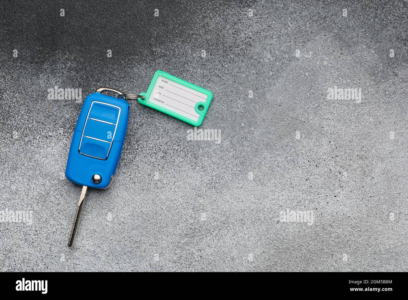 Blauer Autoschlüssel mit Plastikanhänger auf grunge Hintergrund Stockfoto