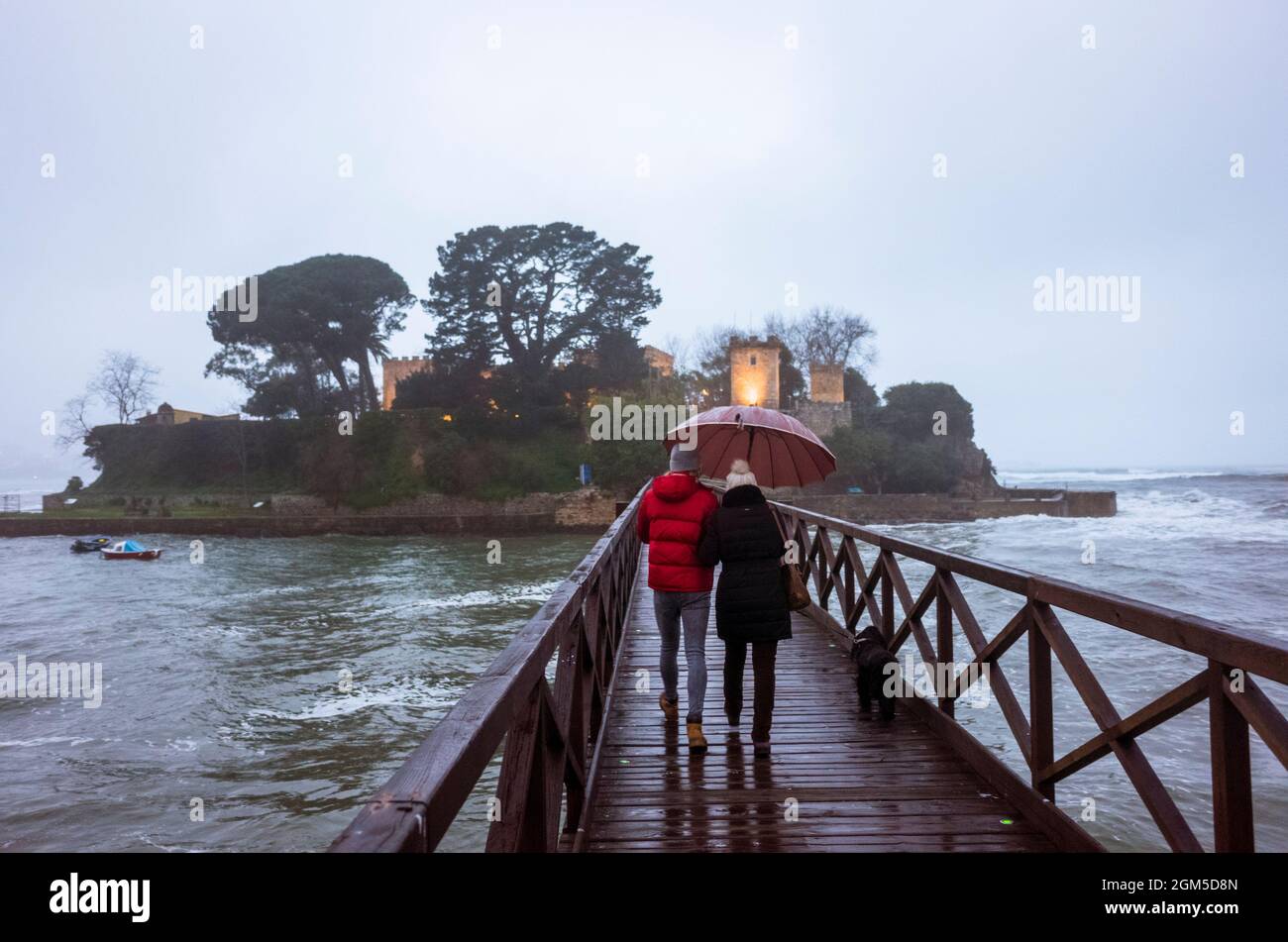 Oleiros, Provinz Coruña, Galicien, Spanien - 11. Februar 2020 : zwei Personen, die einen Regenschirmspaziergang auf der Fußgängerbrücke in Richtung Santa Cristina isl machen Stockfoto