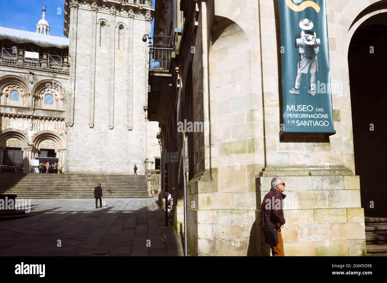 Santiago de Compostela, Provinz Coruña, Galicien, Spanien - 12. Februar 2020 : Ein Mann geht am Wallfahrtmuseum und der Südfassade des vorbei Stockfoto