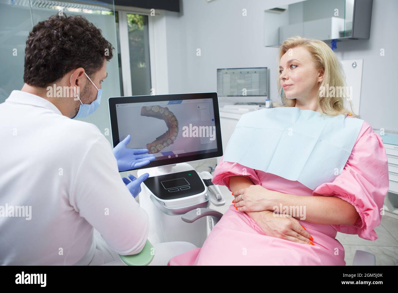 Reife Frau, die mit ihrem Zahnarzt über ihren Zahnscan spricht Stockfoto