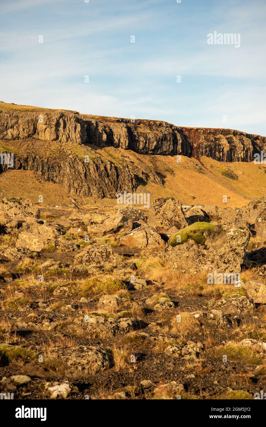 Isländische Topographie mit warmen Braun- und Orange-Tönen und felsiger Struktur mit blauem Himmel Stockfoto