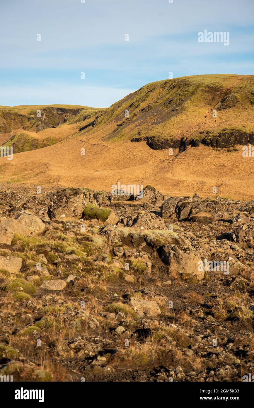 Isländische Topographie mit warmen Braun- und Orange-Tönen und felsiger Struktur mit blauem Himmel Stockfoto
