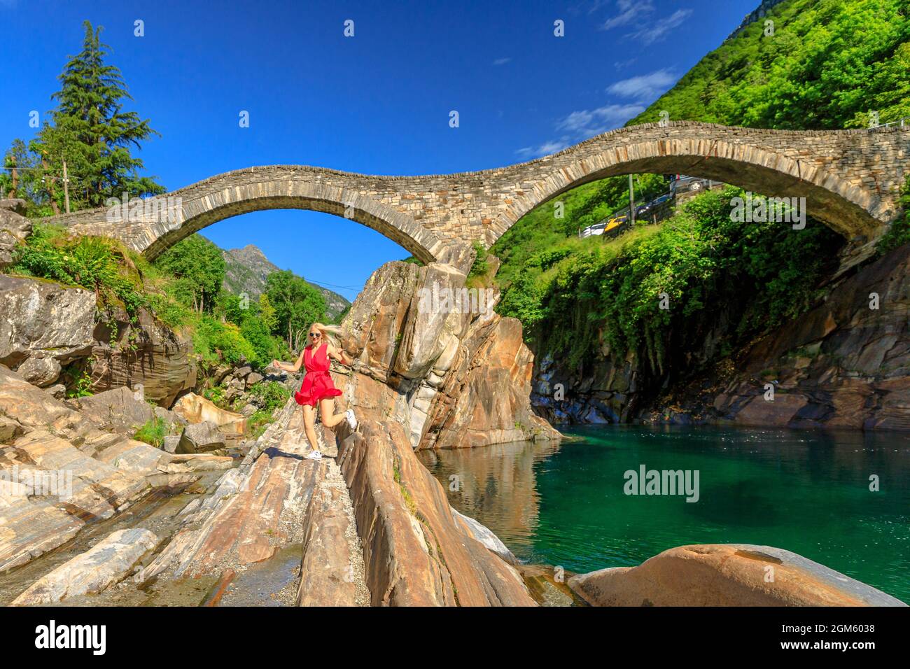 Frau, die unter der römischen Steinbrücke läuft: Ponte dei Salti über dem Verzasca-Fluss. Verzasca Tal bei Lavertezzo. Berühmtes Wahrzeichen für Freizeit am Fluss und Stockfoto