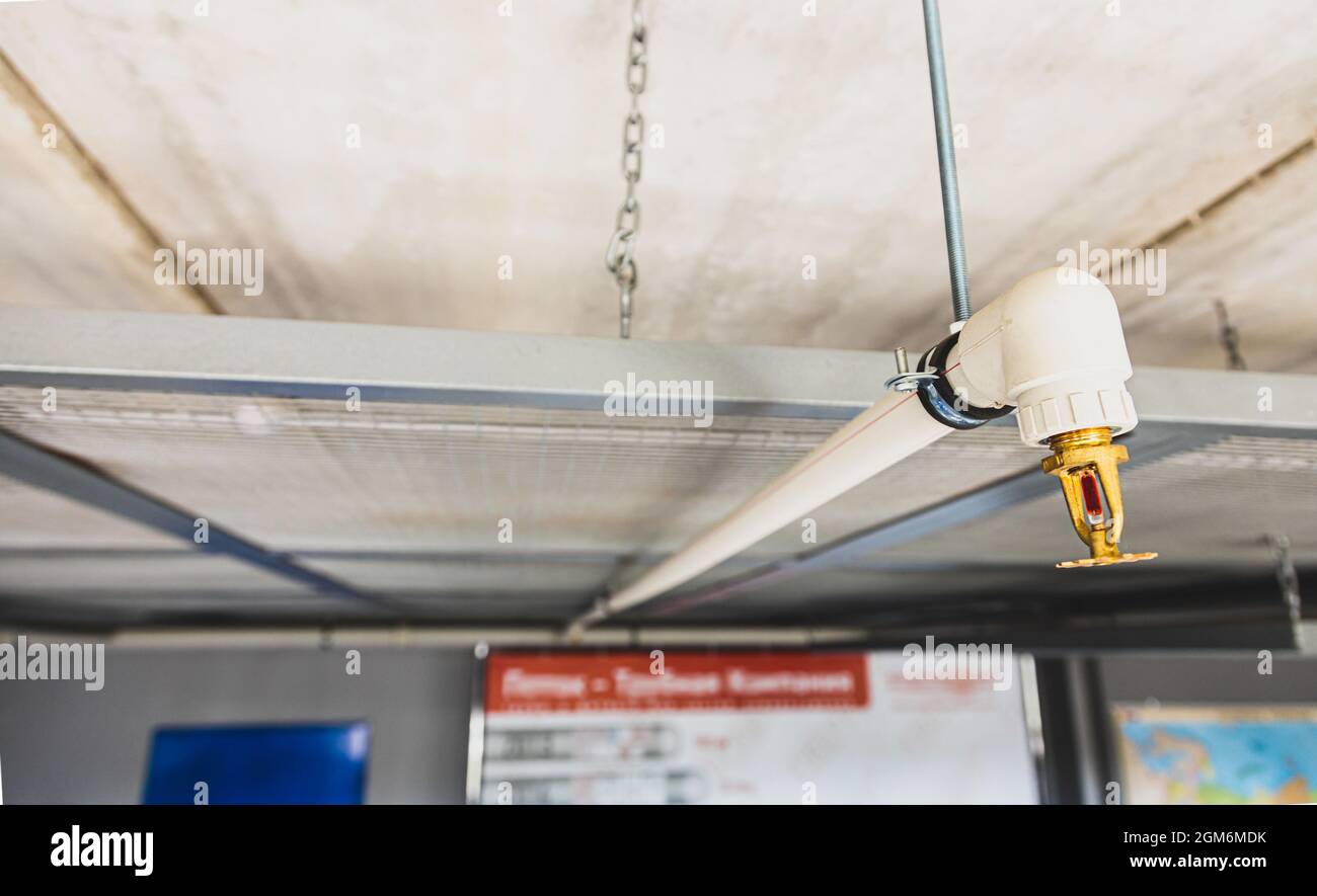 Nahaufnahme des Sprinklerschutzes mit Feuer im Hintergrund. Die Sprinkler sind Teil einer integrierten Wasserleitung, die für Leben und Feuer ausgelegt ist Stockfoto