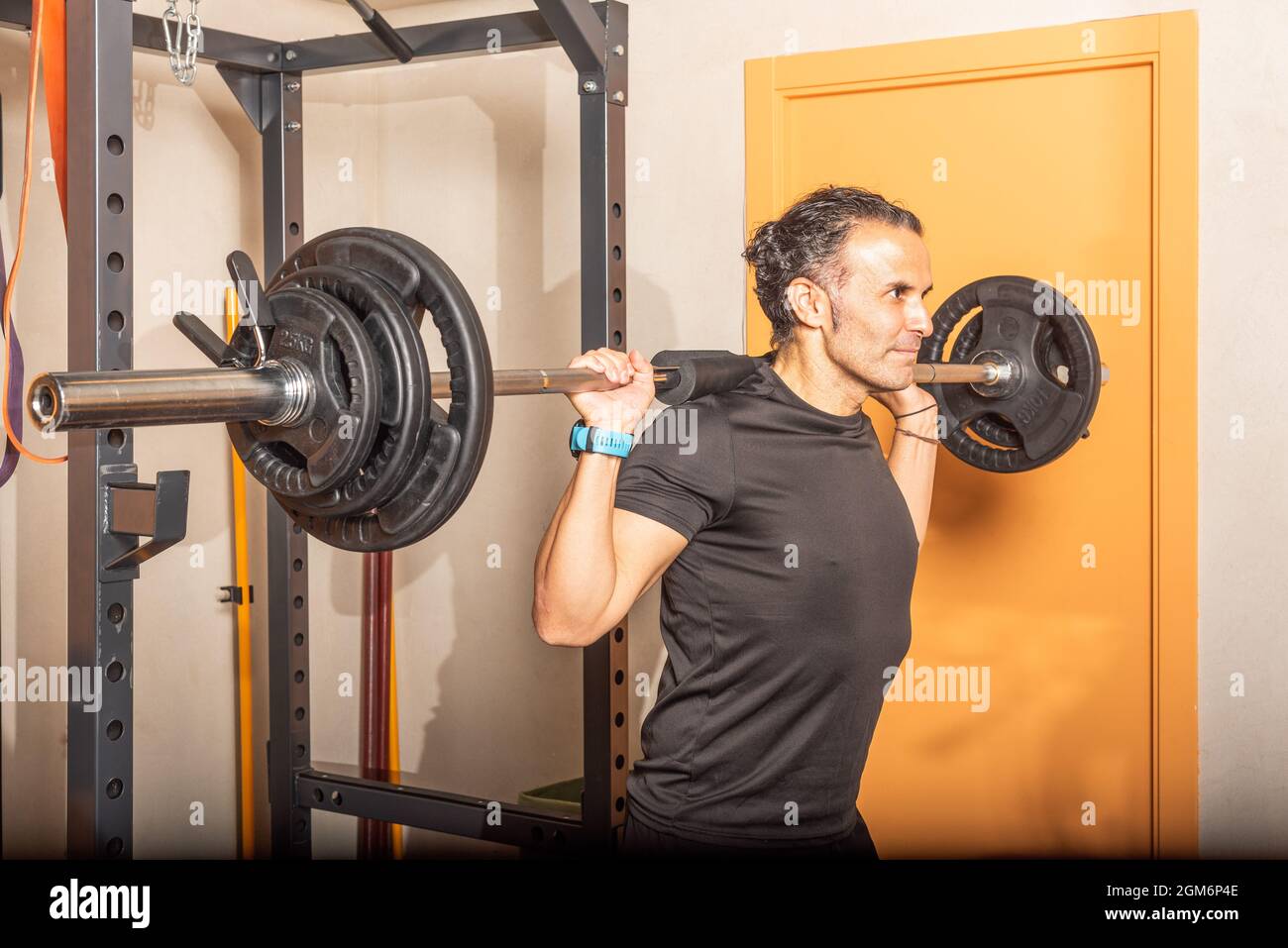 Nahaufnahme eines Sportlers, der mit der Bar im Fitnessstudio hockt Stockfoto