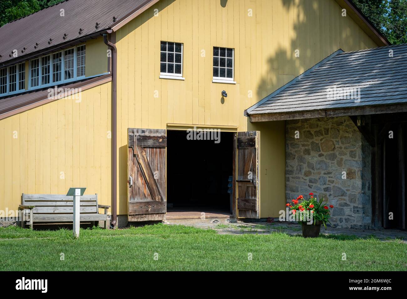 Eine historische gelbe Scheune mit geöffneten Stalltüren. Stockfoto