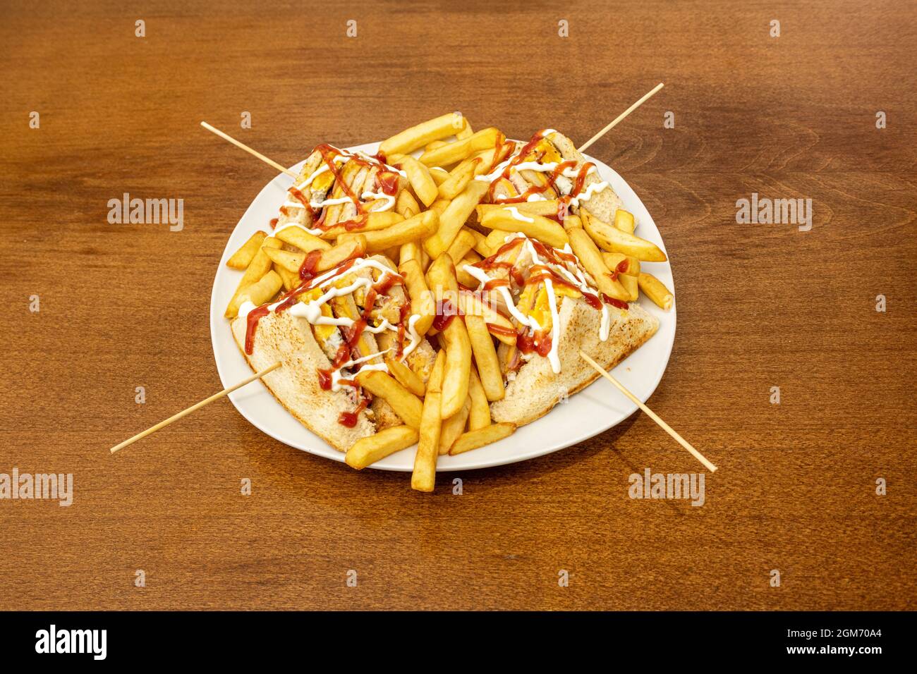 Club-Sandwich mit Essstäbchen in Durcheinander mit pommes auf weißem Teller punktiert Stockfoto