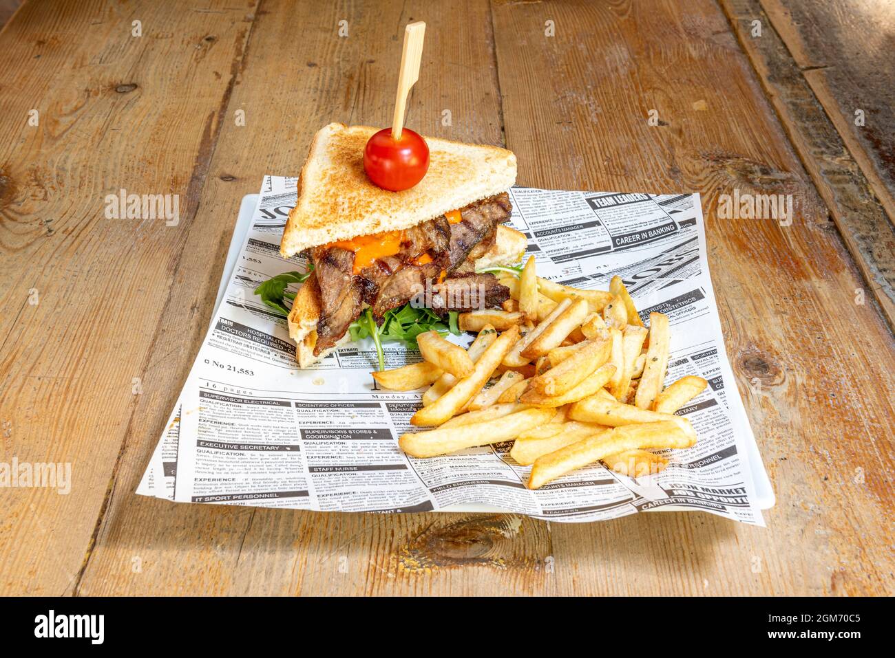 Roastbeef-Sandwich mit Rucola, Kirschtomate, geschmolzenem Cheddar und Pommes frites Stockfoto