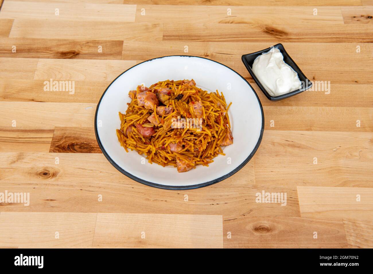 Eine Portion typisch valencianischer Fideua mit Aioli-Sauce auf einem Holztisch Stockfoto