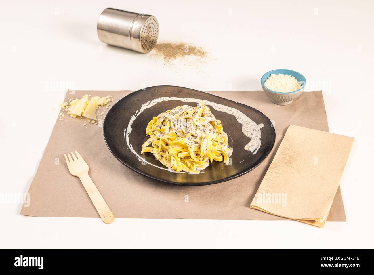 Schönes Nudelgericht mit köstlichem Tagliatelle tartufata Rezept mit geriebenem Käse und Parmesan-Flocken auf einem weißen Tisch. Stockfoto