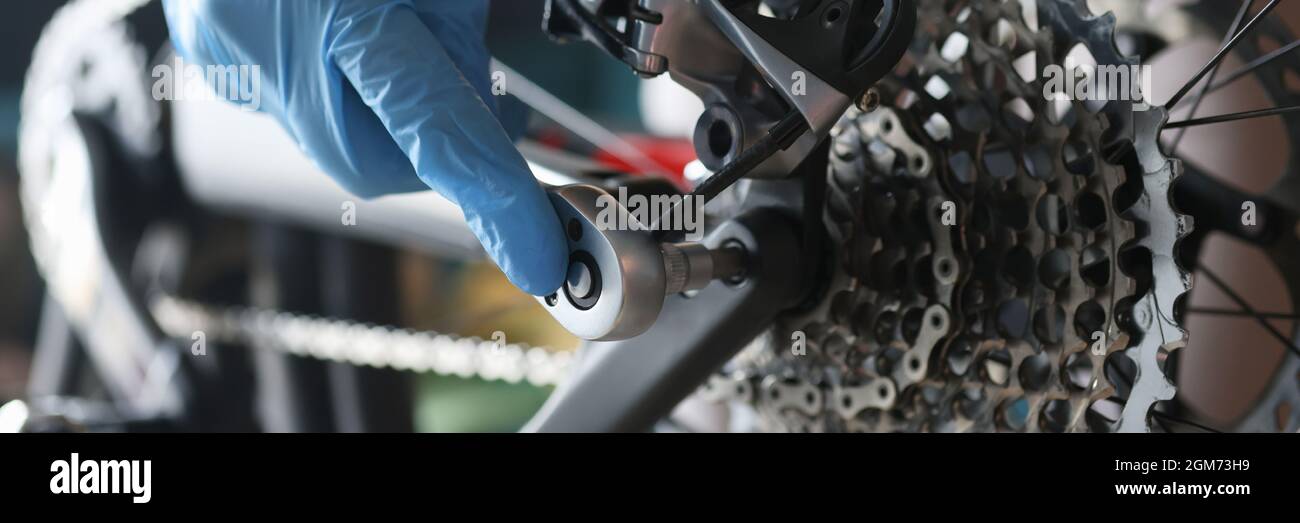 Handwerker in Gummihandschuhen Reparatur Fahrrad in der Werkstatt Nahaufnahme Stockfoto