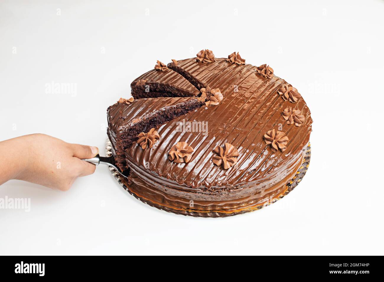 Eine Portion Schokoladenkuchen mit glänzendem Glasur und kleinen Blüten von Mousse herausnehmen Stockfoto