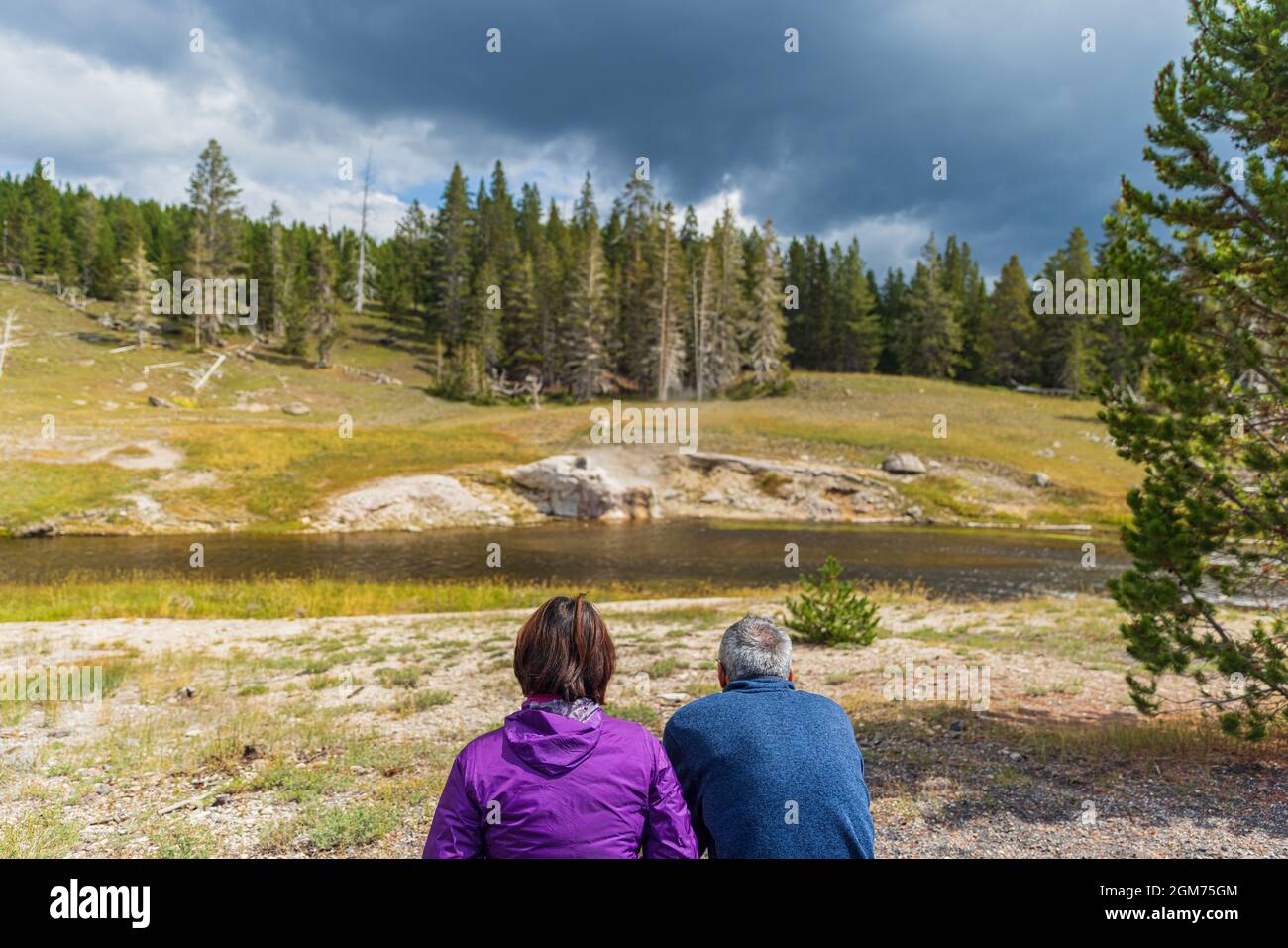 Paar warten auf den Ausbruch des Riverside Geyser im Old Faithful Basin, Yellowstone National Park Stockfoto