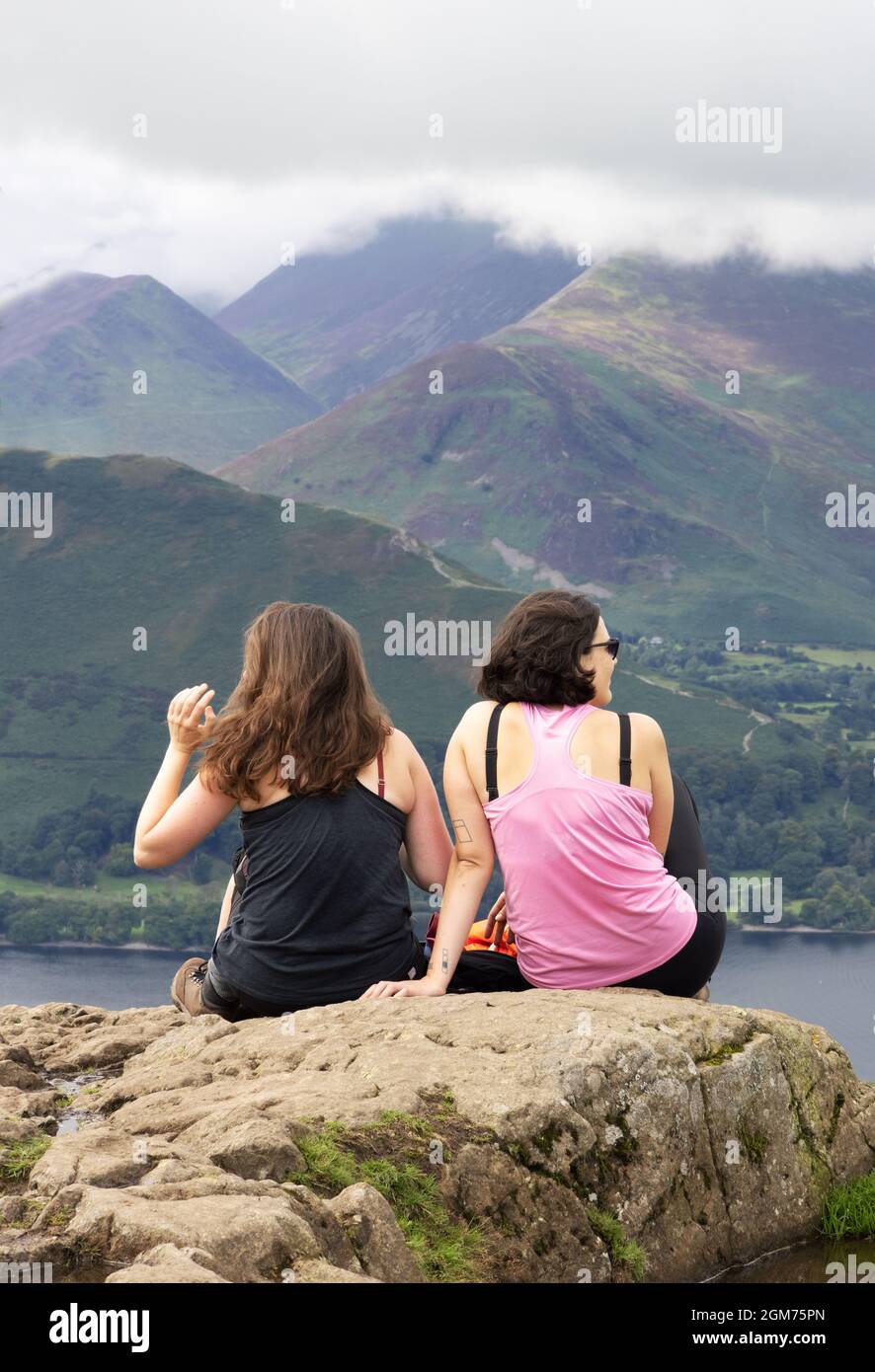 Reisen nach Großbritannien; Touristen aus dem Lake District - zwei Frauen sitzen auf dem Walla Crag und genießen den Blick über Derwentwater, Lake District National Park, Cumbria UK Stockfoto