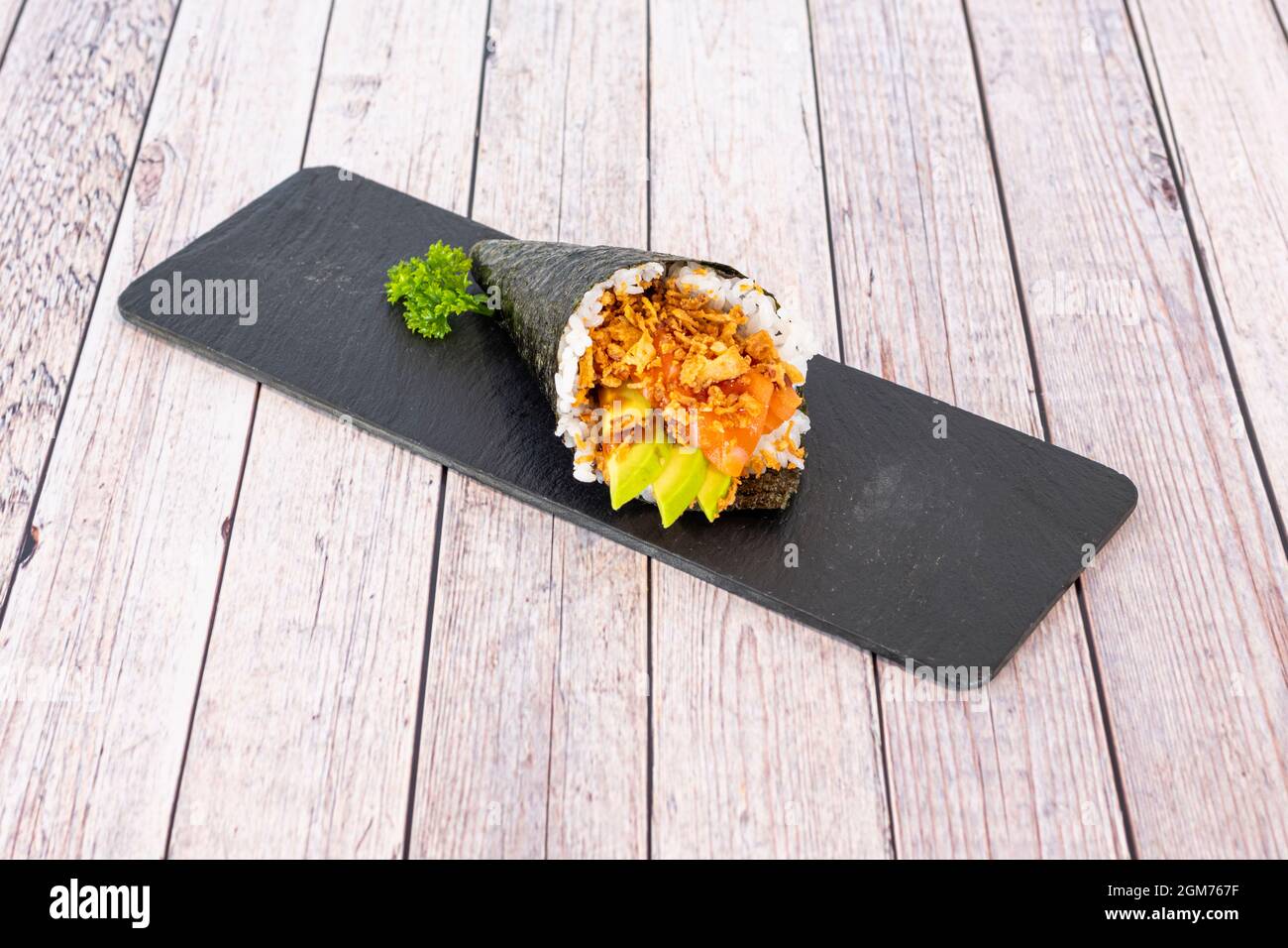 Temaki-Sushi mit norwegischem Lachs, reifen mexikanischen Avocado, knusprigen Zwiebeln und weißem Reis mit Essig und Nori-Algen-Kegel Stockfoto
