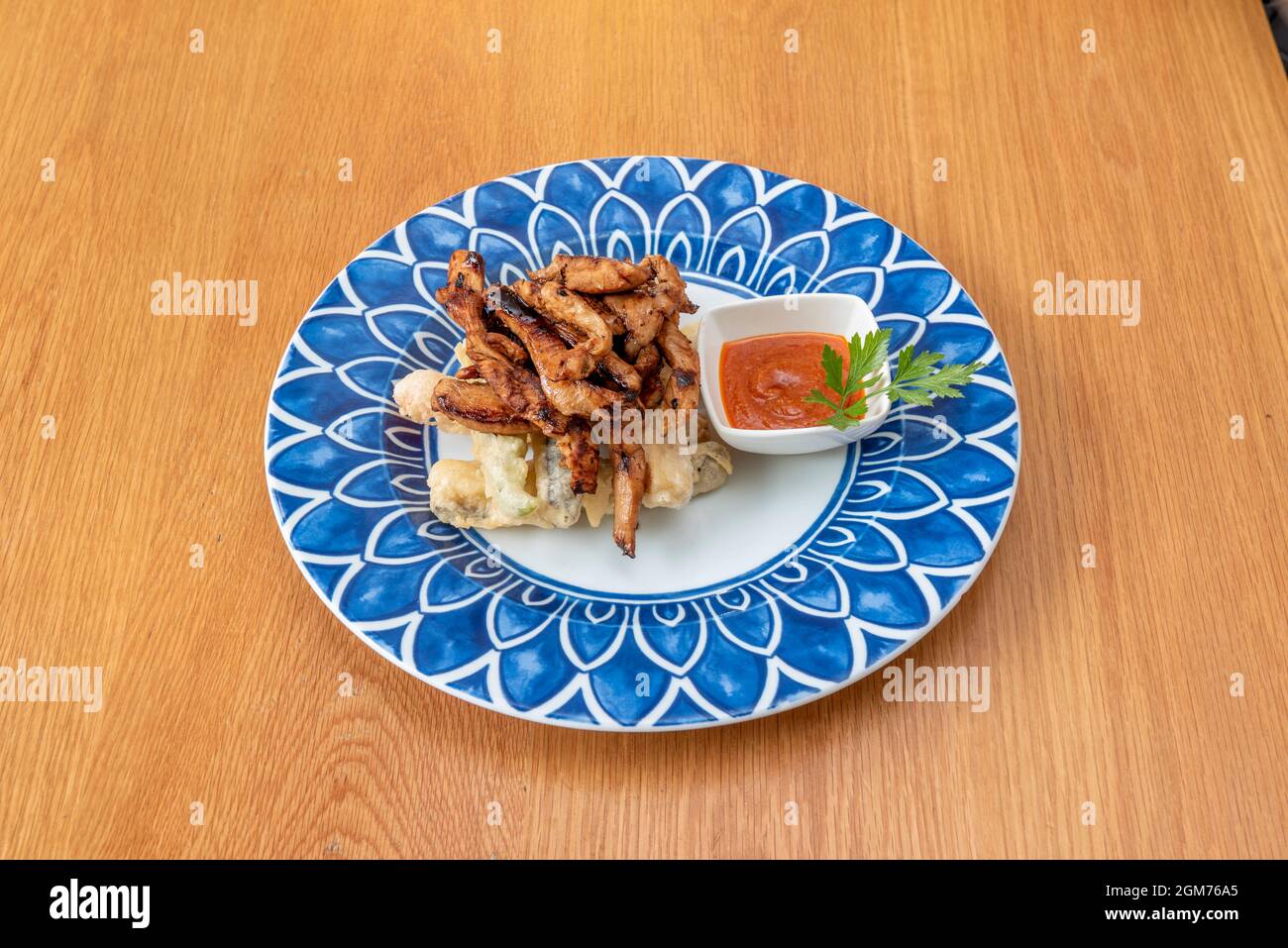 Verschiedene Gemüsetempura und gegrillte Chicken Strips mit Dipping Sauce Stockfoto