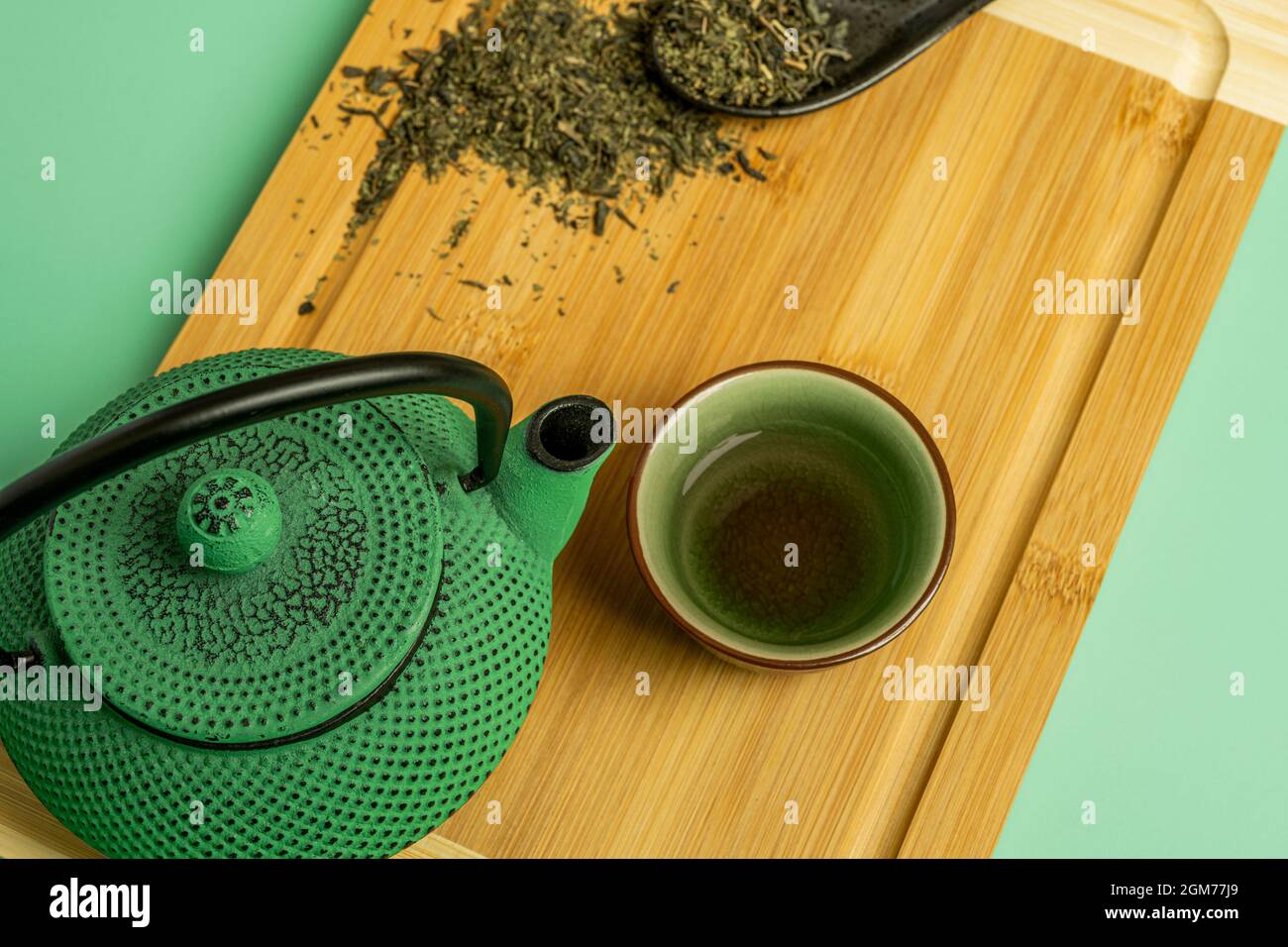 Grüne Teekannen aus Gusseisen, von oben betrachtet, begleitet von einer  kleinen Tasse traditionellen Tees und einem schwarzen Porzellanlöffel mit  dehydriertem Tee Stockfotografie - Alamy