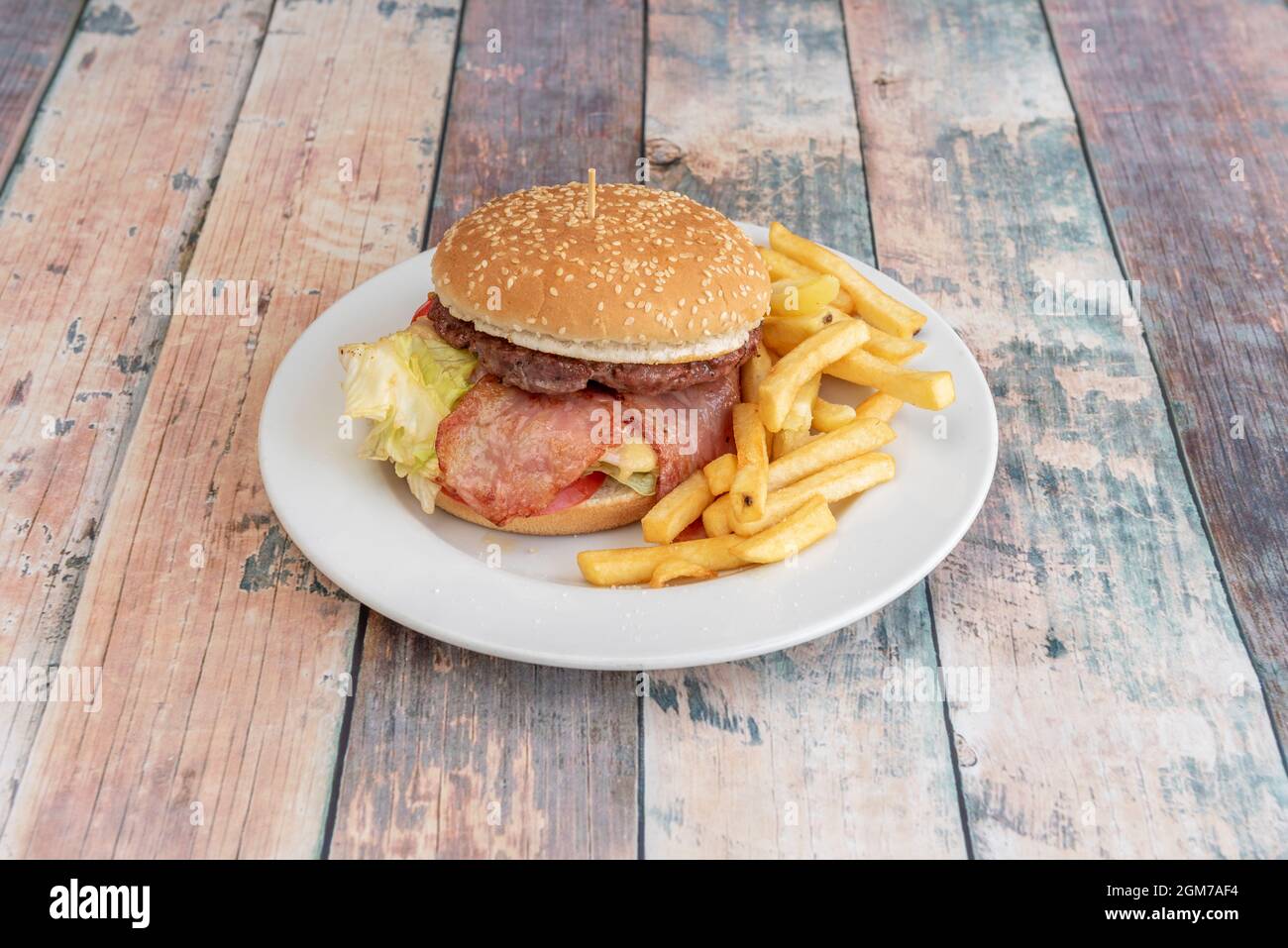 Rinderburger mit Speck, Ziegenkäse, geschmolzenem Käse, Tomaten und Salat und einer Portion Pommes Frites Stockfoto