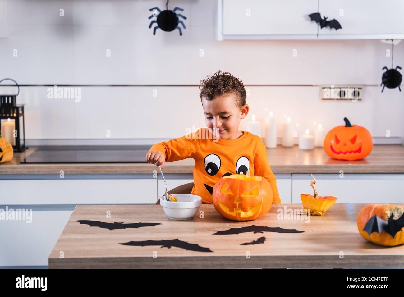 Kind als halloween Kürbis T-Shirt gekleidet Entleeren und Dekorieren eines halloween Kürbis in der Küche zu Hause. Stockfoto