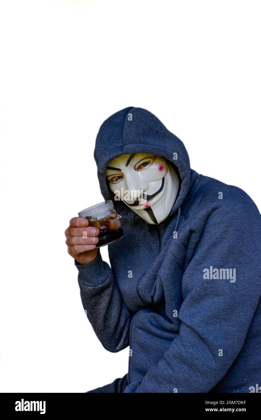 Anti-Impfstoff-Verschwörungstheoretiker mit Kapuzenpullover und V für Vendetta Maske Toast mit Glas Alkohol Stockfoto