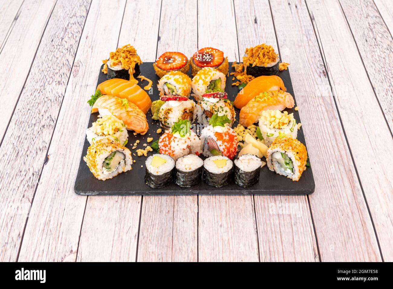 Gemischtes Sushi-Tablett mit Nori-Algen-Maki, Uramaki california Roll mit Masso-Rogen, rohem Lachs Nigiri, flambiertem Lachs, knusprigen Zwiebeln, Frischkäse und Stockfoto