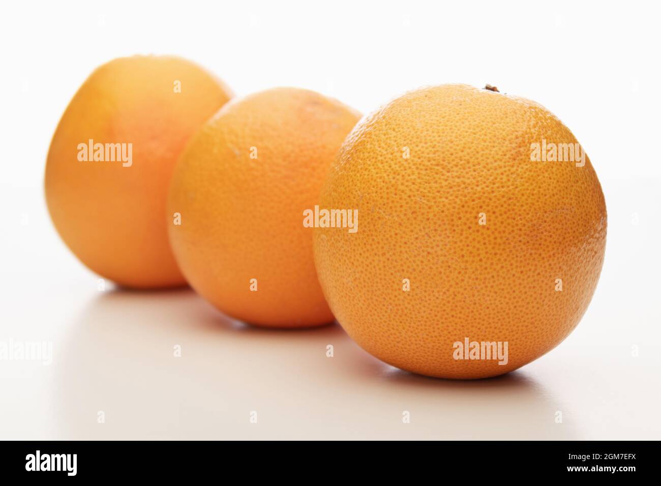 Drei ganz orange Grapefruits isoliert auf weißem Hintergrund, zwei von ihnen sind unscharf, Bokeh Stockfoto