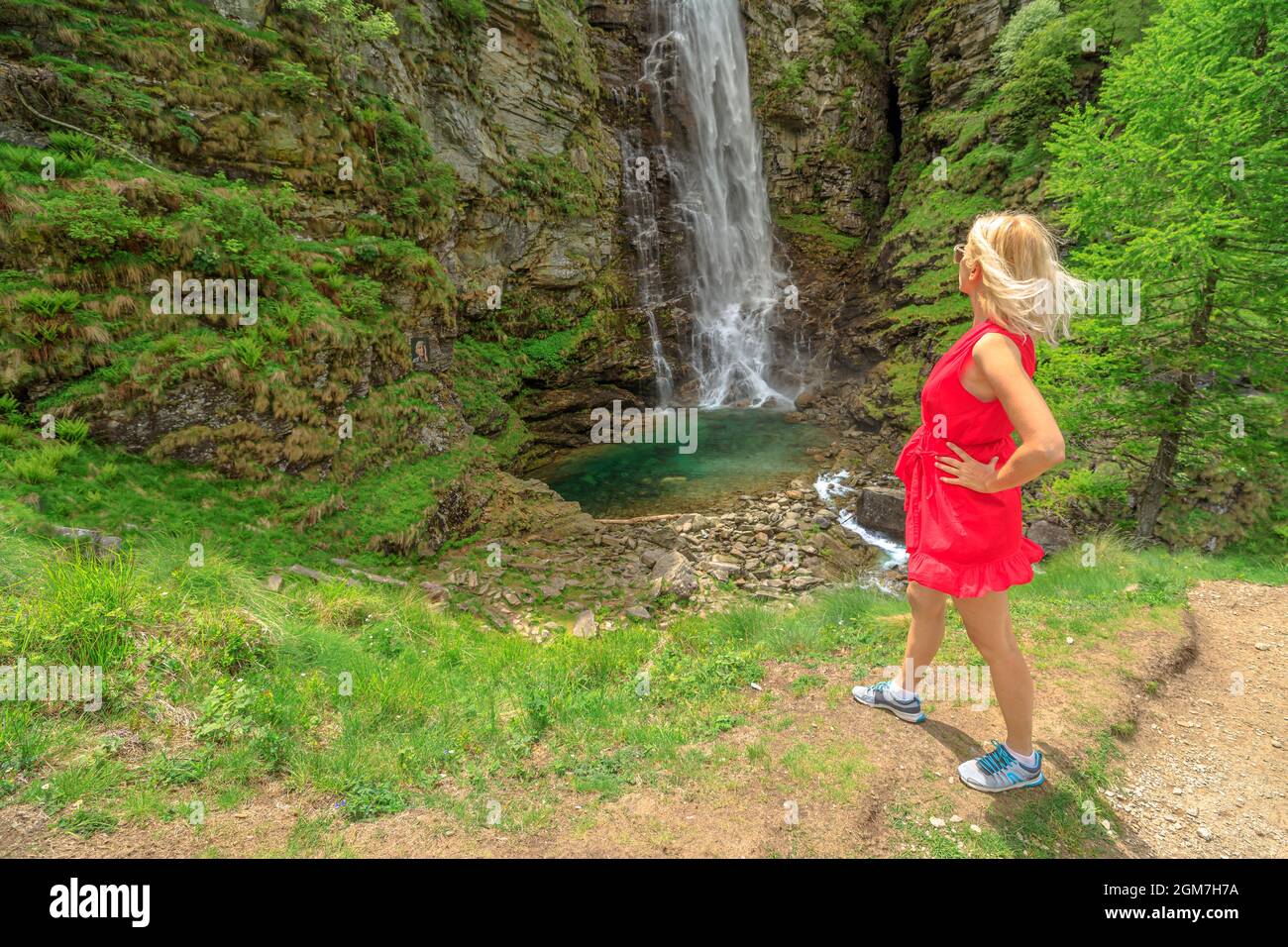 Frau, die den Froda Wasserfall oder den Sonogno Wasserfall über den Riale Kard Fluss in Sonogno Stadt in der Schweiz schaut. Riale kardierte Fluss in Verzasca Stockfoto