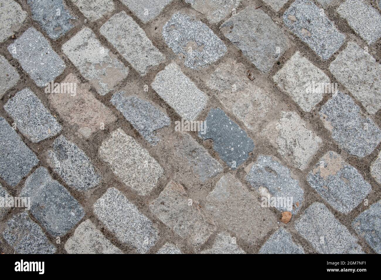 Pflastersteine einer Straße, die auf der Diagonale des Rahmens gepflastert ist. Vektor Granit Textur Hintergrund Stockfoto