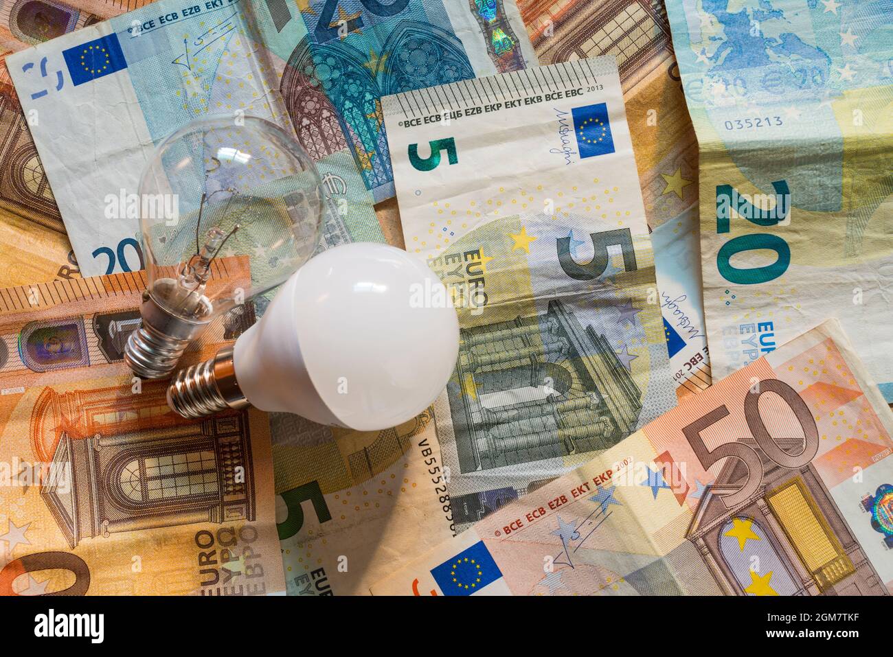 Glühbirnen auf einem Hintergrund von Euro-Banknoten. Konzept der steigenden Strompreise. Stockfoto