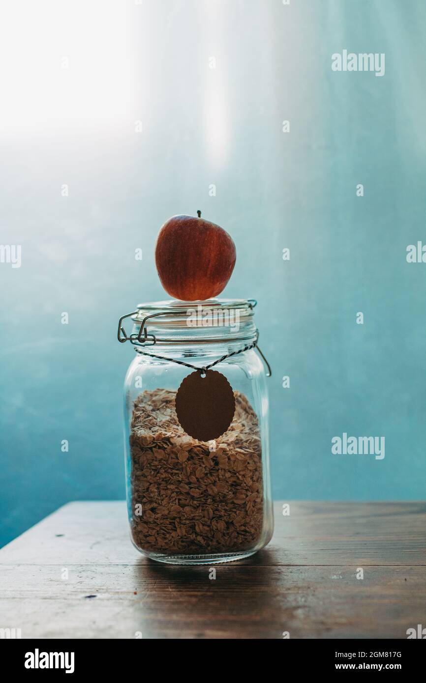 Toller Start in den Tag - isolierte Apfel- und Haferflocken im Glas auf blauem Hintergrund Stockfoto