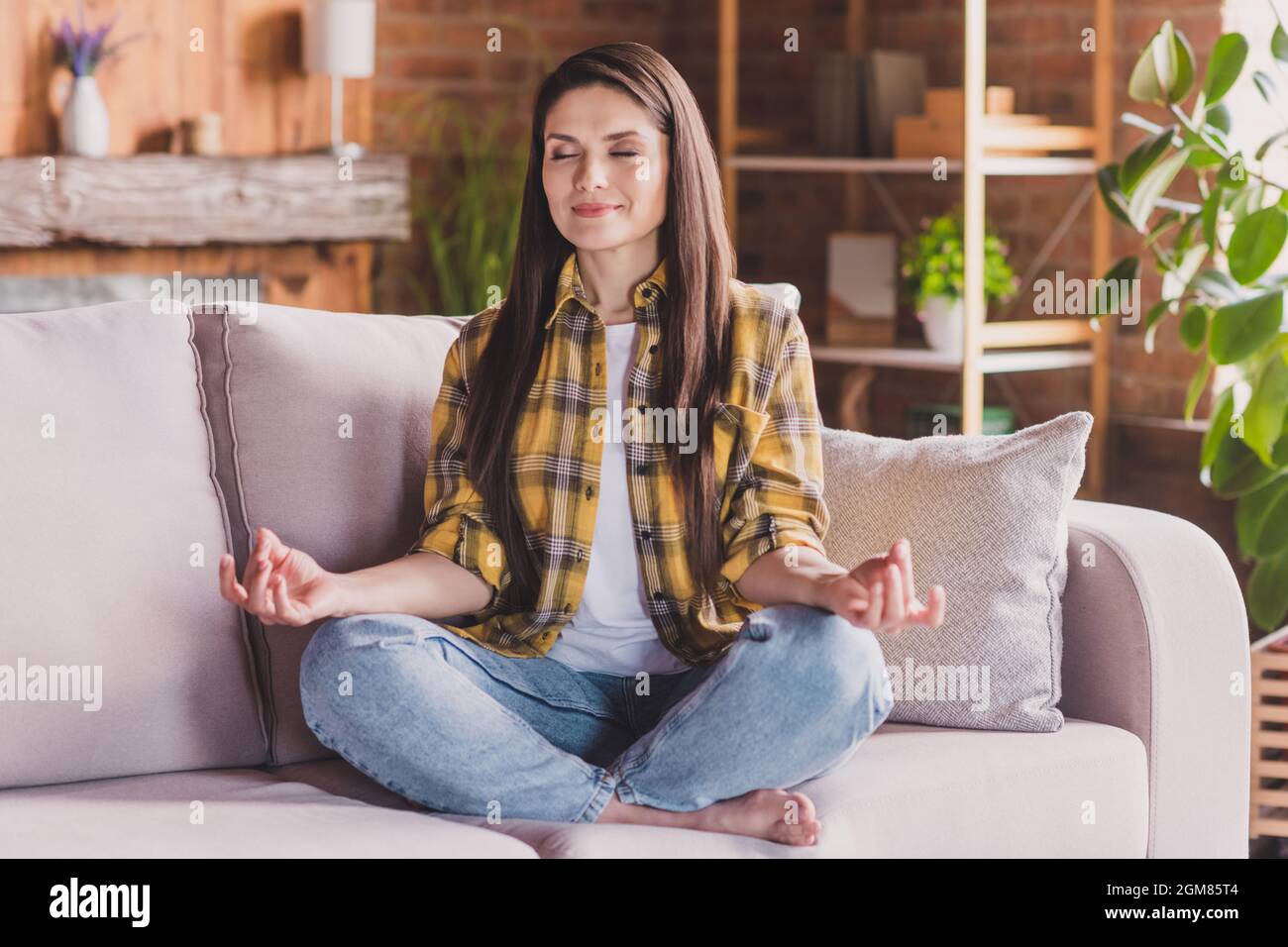 Foto von friedlichen sportlichen Dame üben Yoga-Training barfuß sitzen gemütliche Couch tragen kariertes Hemd zu Hause drinnen Stockfoto