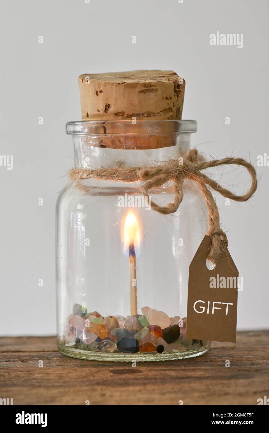 Geschenk Abhalten. Glas mit Match Stick Gezündete Flamme des brennenden Feuers und Edelsteinen Stockfoto