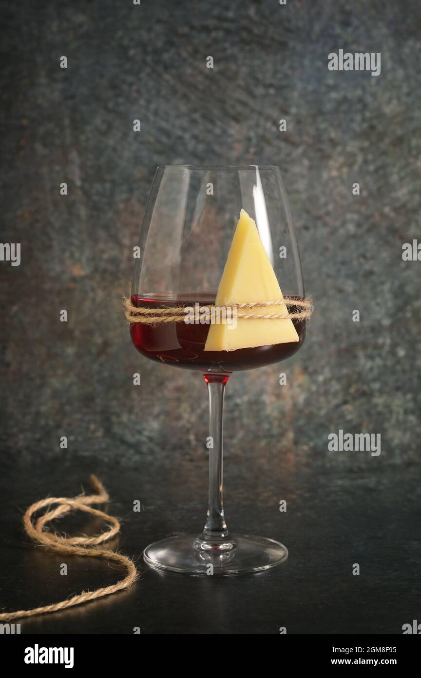 Trockenes Glas Rotwein und Käse auf steinernem Hintergrund Stockfoto