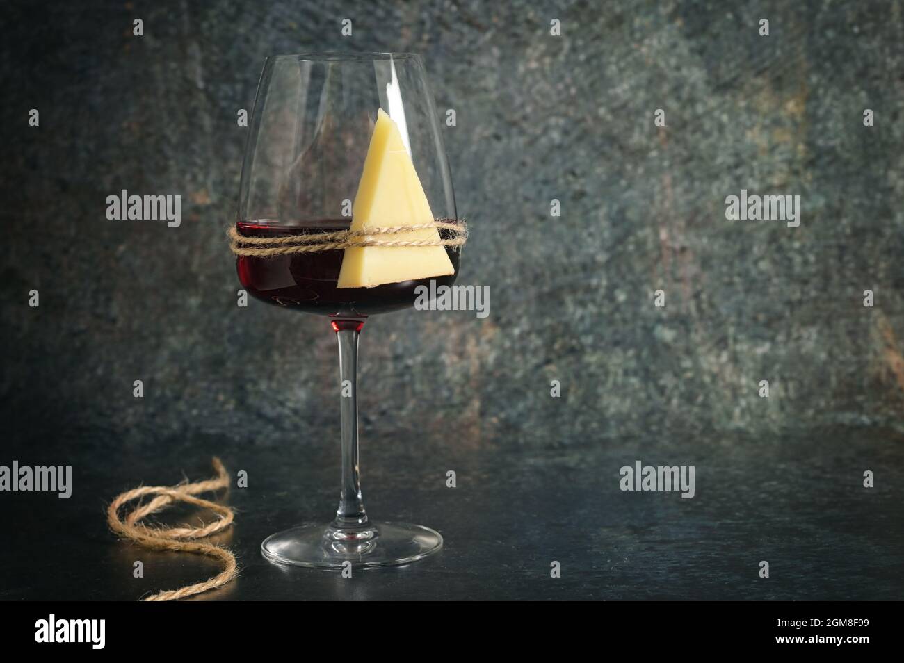 Trockenes Glas Rotwein und Käse auf steinernem Hintergrund Stockfoto