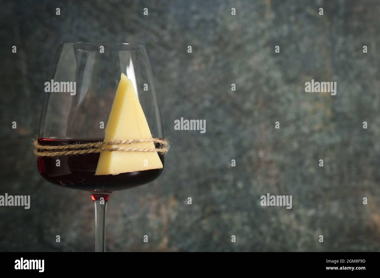 Trockenes Glas Rotwein und Käse auf steinernem Hintergrund Stockfoto